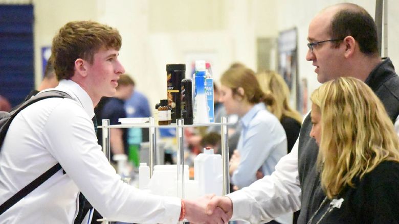 A student shakes hands with a corporate recruiter at Penn State Behrend's Career and Internship Fair.
