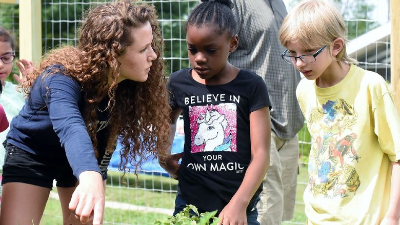 Penn State Behrend student Celeste Makay gives two younger students a tour of the campus garden.