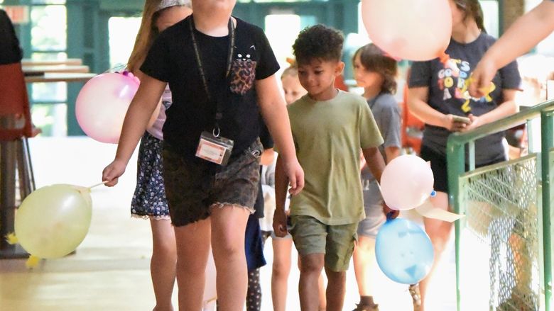A group of children carry balloons in a parade at Penn State Behrend.