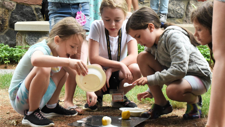 Three girls conduct a science experiment outdoors during Penn State Behrend's College for Kids program.