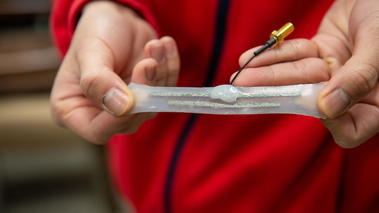 A white membrane with an attached wireless antenna is stretched between a person’s hands. 
