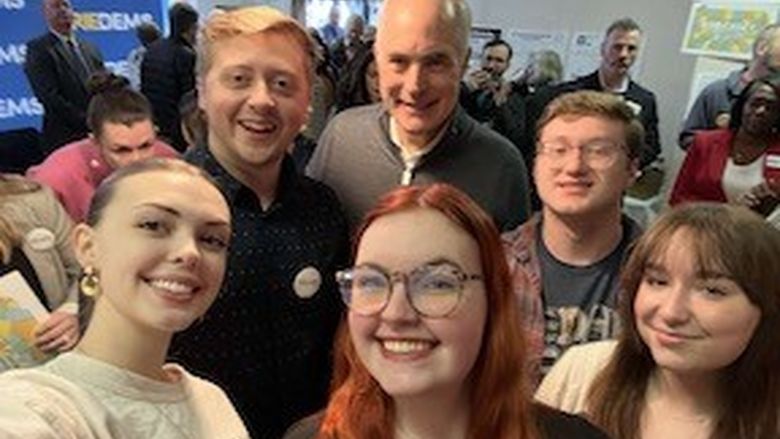 A group of students stand with a male politician