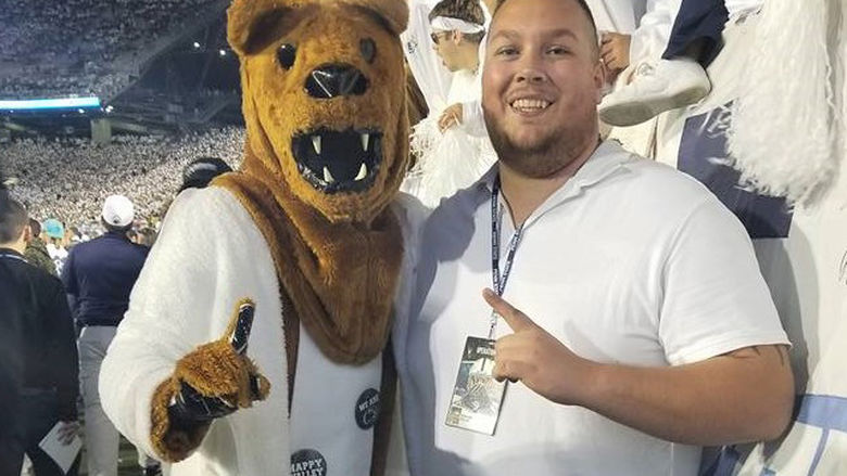 Penn State Behrend alumnus Colten Brown poses with the Nittany Lion at a White-Out game.