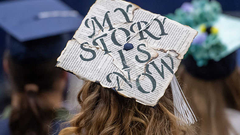 A mortarboard decorated to say "My Story Is Now"