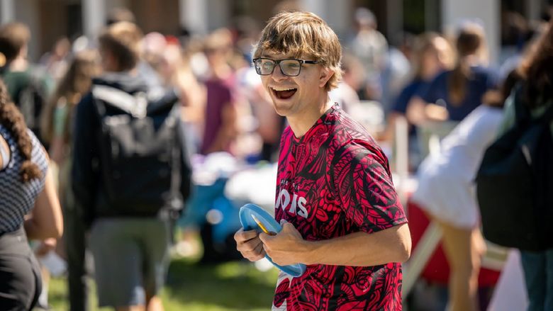 A male student laughs while holding a Frisbee at Penn State Behrend's Discovery Fair.