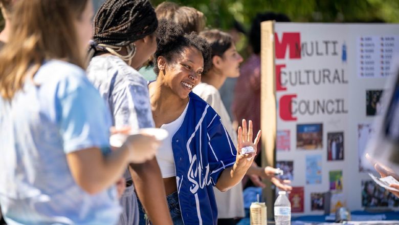 A group of female students laughs while talking at a table at Penn State Behrend's Discovery Fair.