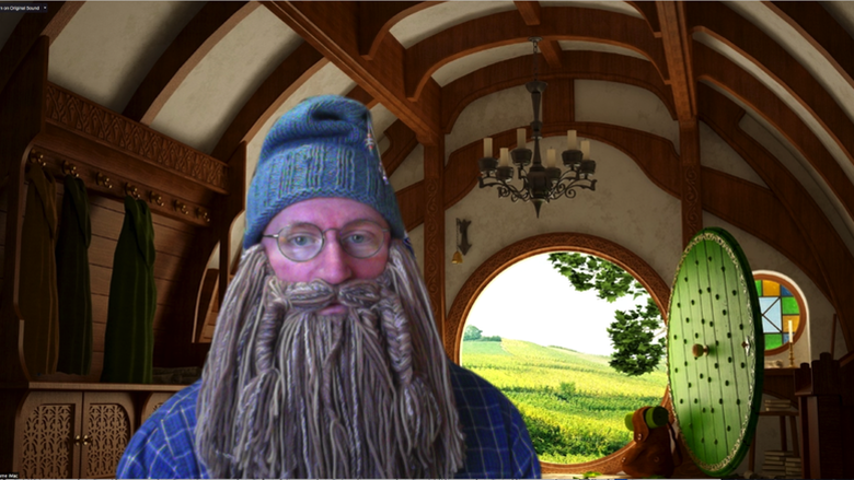man dressed as Gandalf from The Hobbit movie standing in front of Hobbit-themed virtual background