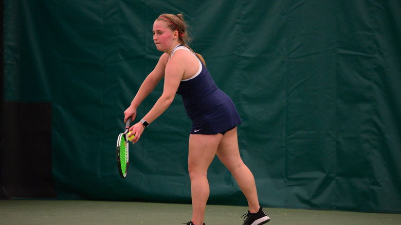 A Penn State Behrend tennis player prepares to serve.