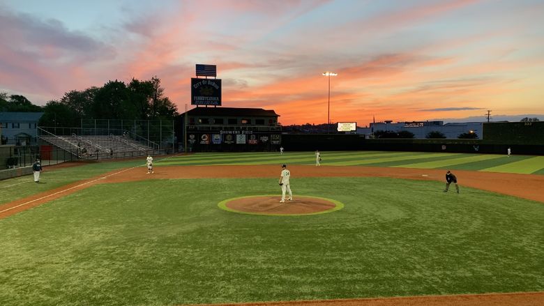 Baseball players at Shower's Field with a sunset.
