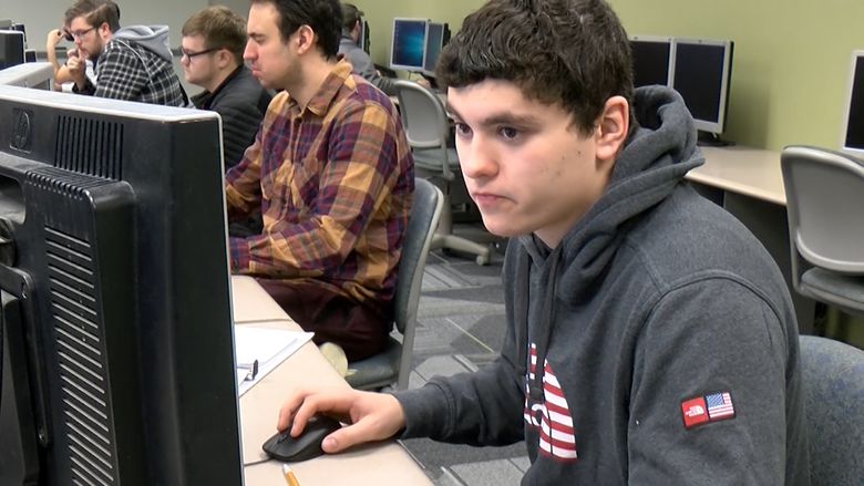 Male students work at computers in a computer lab.