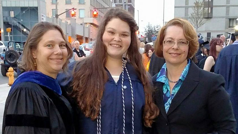 Erica Edwards wearing a gradution gown and posing with two professors