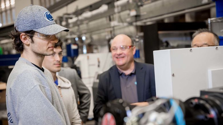 Two students stand at an injection-molding machine at Penn State Behrend.