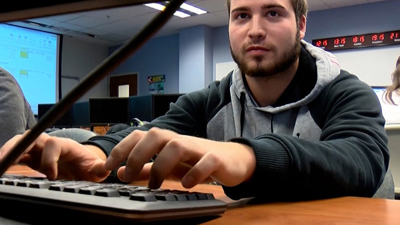 A male students types on a keyboard in the finance lab.