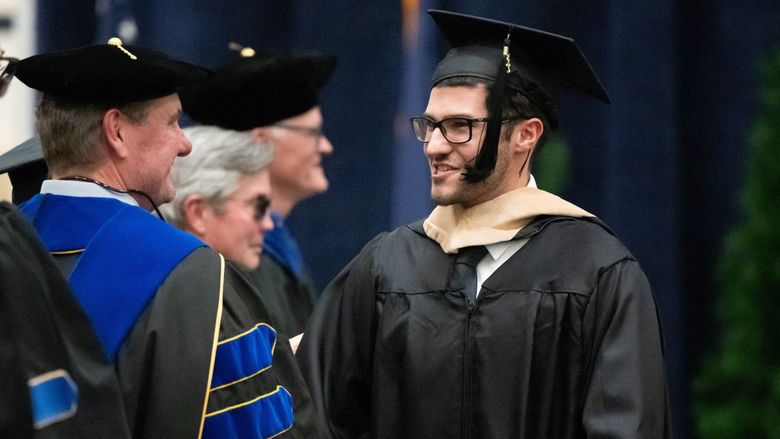 A graduate smiles at a faculty member during Penn State Behrend's commencement program.