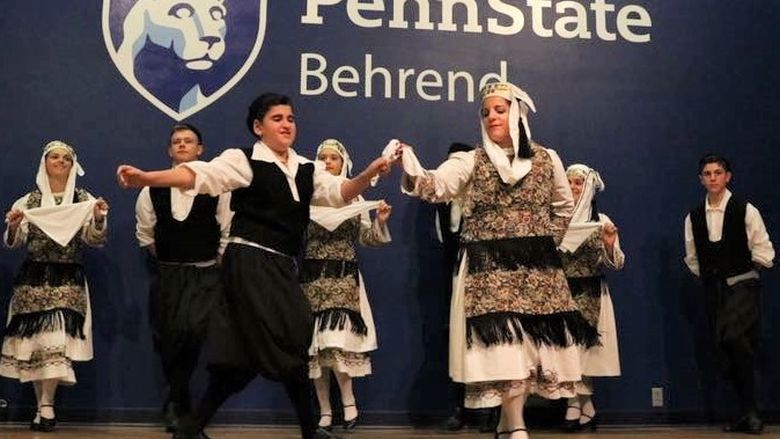 Costumed dancers perform a cultural dance on a stage at Penn State Behrend.