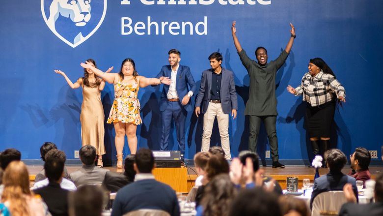 A diverse group of students celebrates on stage at the Harambee Dinner.