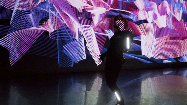 A woman performs against a backdrop of light painting and real-time projection.