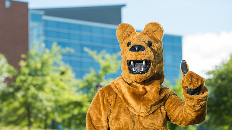 The Penn State Nittany Lion mascot poses in front of Burke Center at Penn State Behrend.