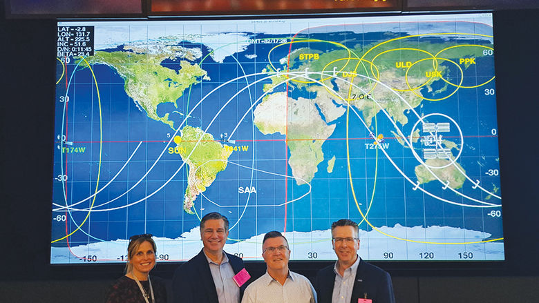 From left, Mary (Good) Lawrence, Tim Kurzweg, Dave Johnson, and Chancellor Ford in front of a world map at NASA’s Johnson Space Center.