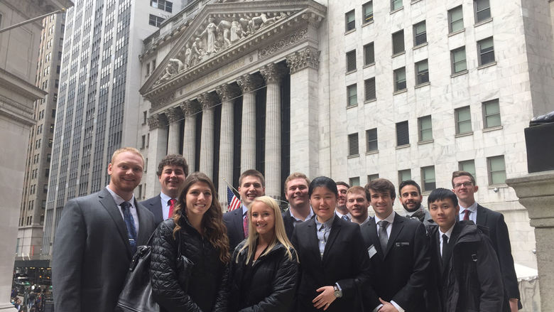 A group of Black School of Business students stand in front of the New York Stock Exchange.