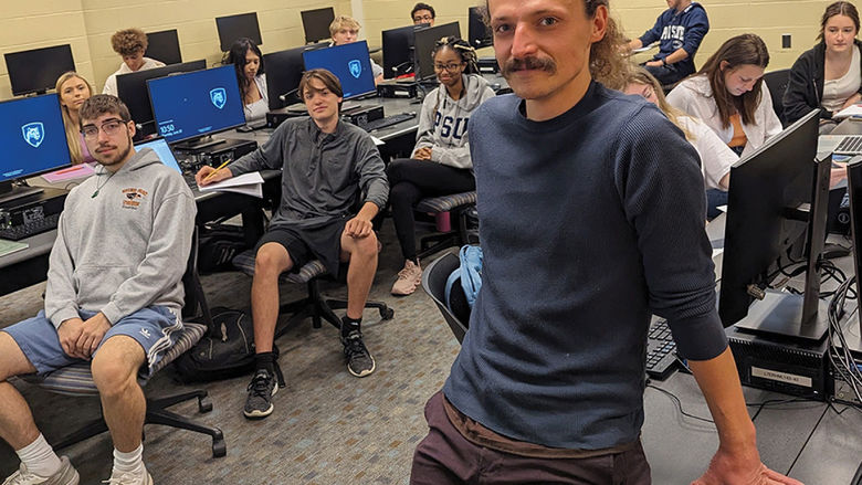 Penn State Behrend faculty member Jasper Sachsenmeier poses in a classroom with several students.