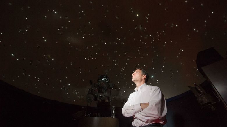 Planetarium director Jim Gavio looks at the stars projected on the ceiling of Yahn Planetarium at Penn State Behrend.