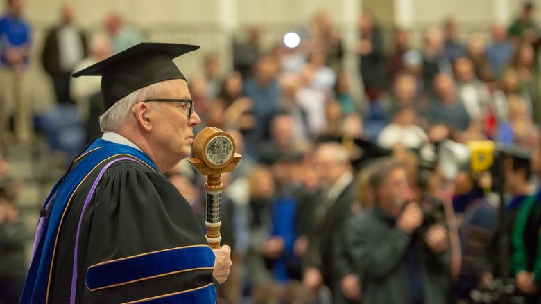 Penn State Behrend faculty member John Gamble carries the college mace at a commencement ceremony.