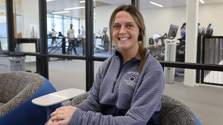 Kelly Wilson, the new campus recreation manager at Penn State Behrend, sits in the lobby of the college's new Erie Hall.