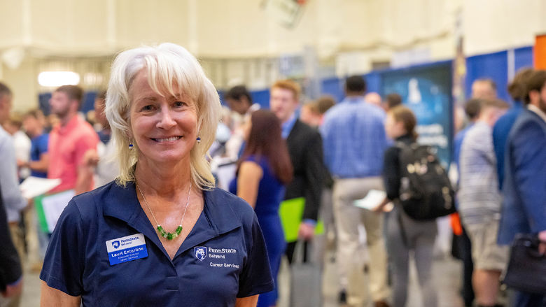 Person smiles at the camera. Crowd mills about in the background.