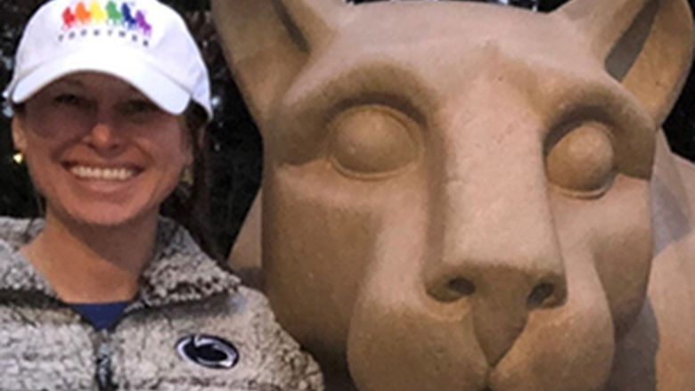 A woman poses next to the Nittany Lion Shrine.