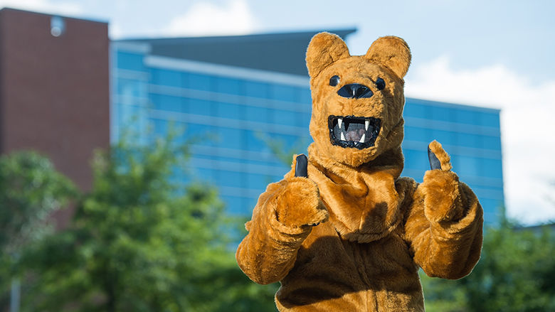 The Penn State Behrend Lion mascot poses in front of Burke Center