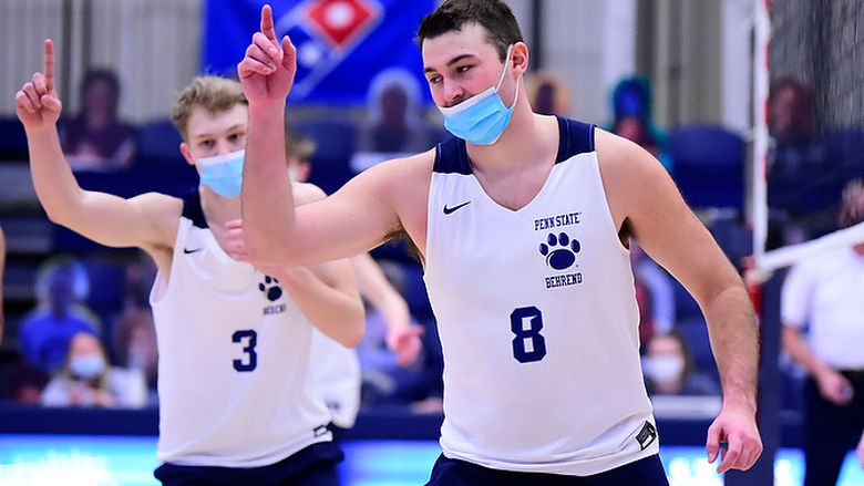 Two members of the Penn State Behrend men's volleyball team celebrate after scoring a point.