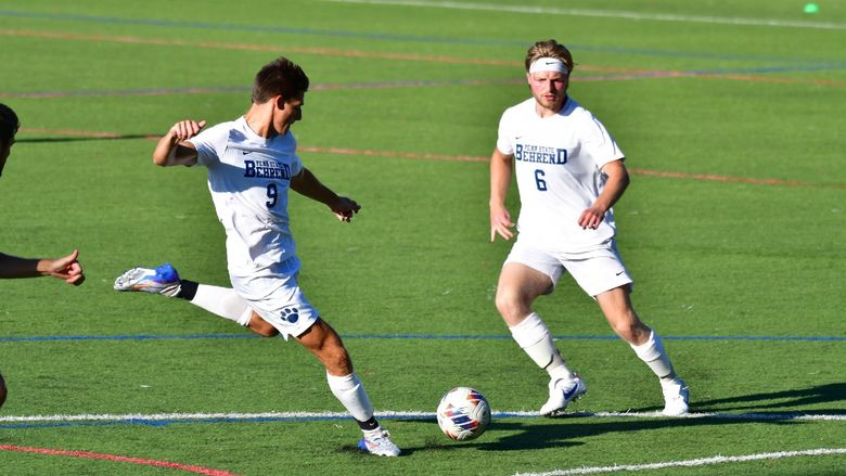 Two members of Penn State Behrend's men's soccer team advance toward the goal.