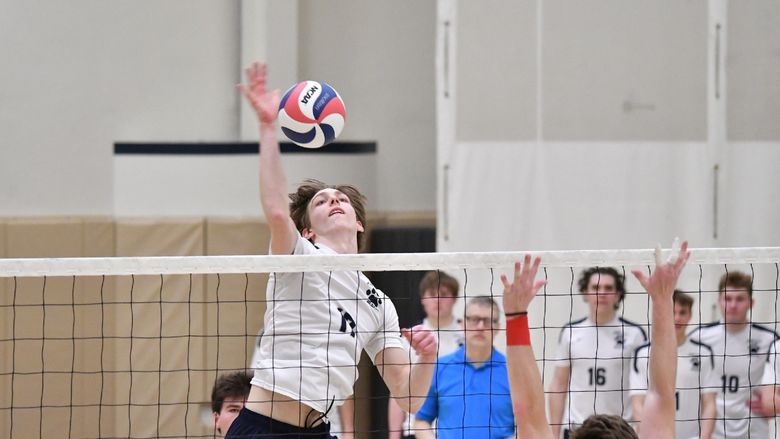 A member of the Penn State Behrend men's volleyball team spikes the ball over the net.