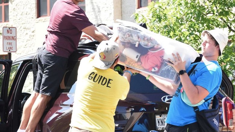 Students help a parent move items from a car during Penn State Behrend's move-in day.
