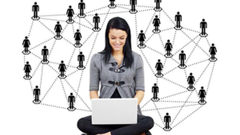 Female with computer on lap and surrounded by web of male and female silhouette icons