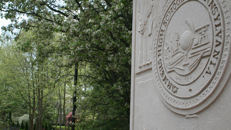 Inscribed pillar behind the of HUB-Robeson Center at Penn State with the words "Farmers High School of Pennsylvania"