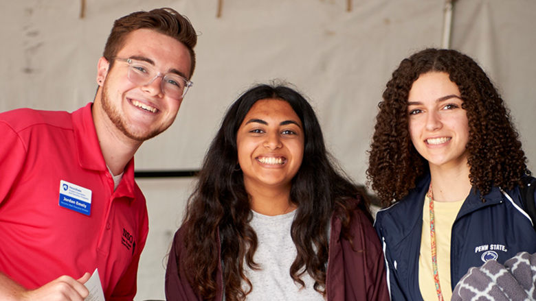 Three students pose together in a group at a new student orientation event.