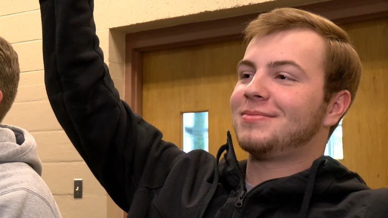 A Physics student at Penn State Behrend raises his hand in class.