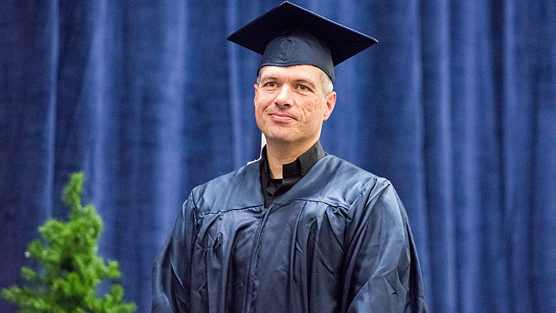 Adult Learner David Lesher at Commencement, wearing cap and gown