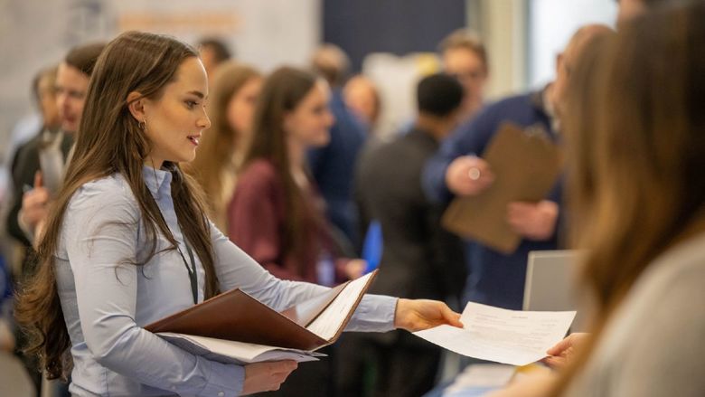 A female student hands a resume to a recruiter at Penn State Behrend's career fair.