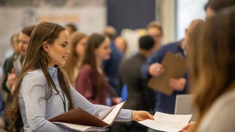 A female student hands a resume to a recruiter at Penn State Behrend's career fair.