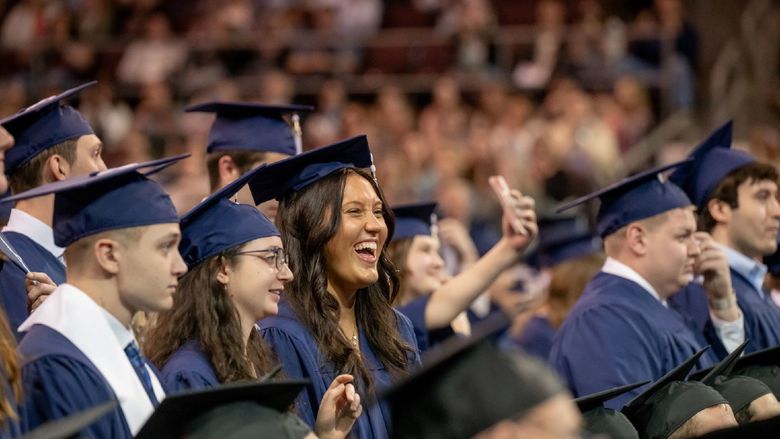 Students smile and point during Penn State Behrend's spring commencement program.