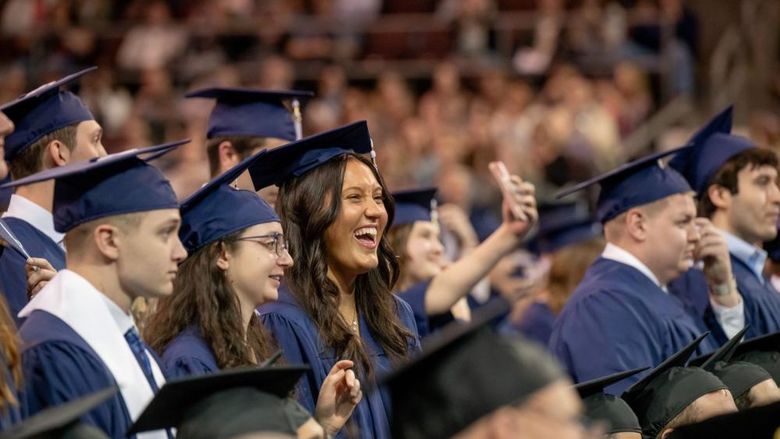 Students smile and point during Penn State Behrend's spring commencement program.