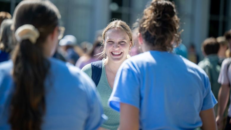A female student smiles while talking to two others at Penn State Behrend's Discovery Fair.