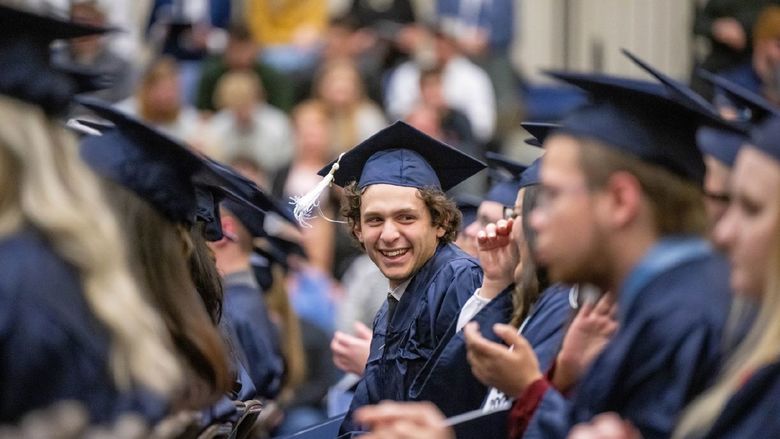 A new graduate turns to look at a classmate during Penn State Behrend's fall 2022 commencement program.