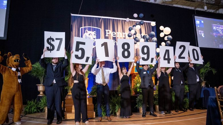 A row of Penn State Behrend students hold up placards with numbers that show the fundraising total in the college's six-year campaign.