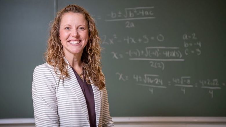 Penn State Behrend faculty member Courtney Nagle poses in front of a chalkboard.