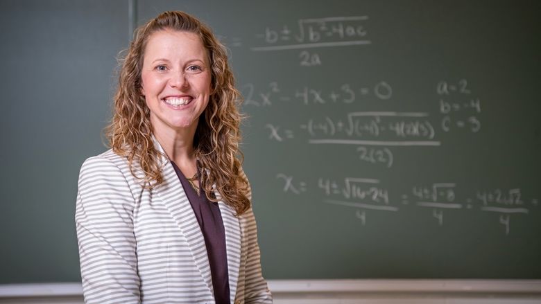 A Penn State Behrend professor explains a math problem while standing in front of a chalkboard.