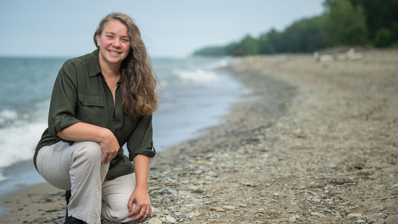 Sherri Mason kneels on the beach at Presque Isle State Park